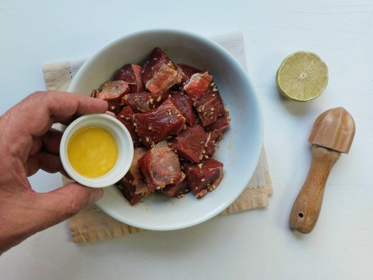 Um recipiente contendo carne sendo temperada.