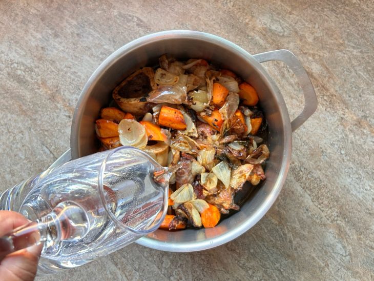 Todos os ingredientes na panela, água sendo adicionada para completar e cobrir tudo.