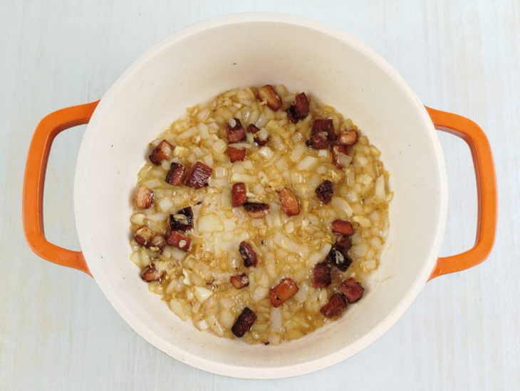 Cebola e alho amassados adicionados ao bacon.