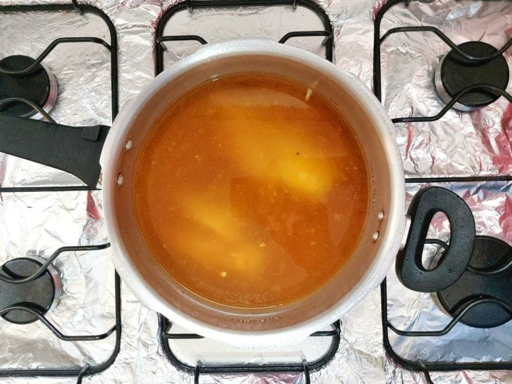 Uma panela de pressão cozinhando frango com vegetais e temperos.