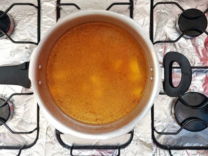 Uma panela de pressão cozinhando batatas com caldo de frango.