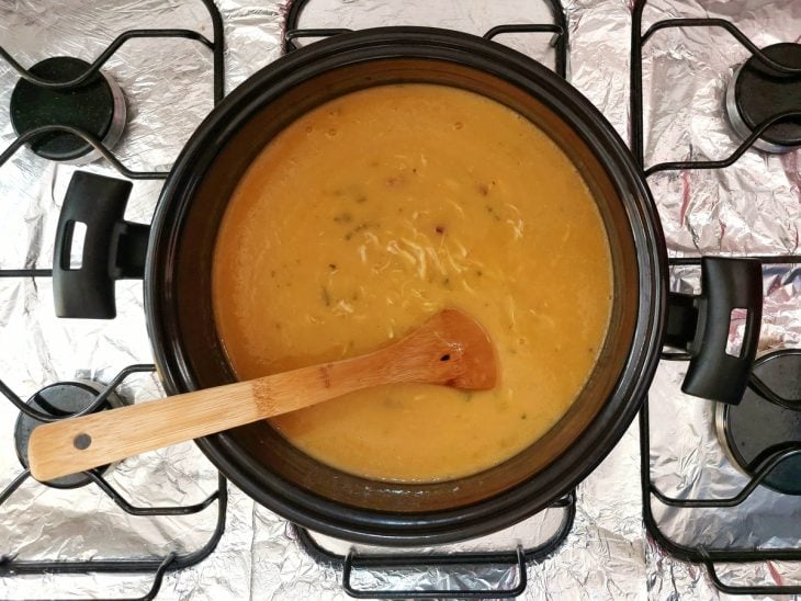 Uma panela contendo a mistura de batata e caldo, com o frango desfiado.