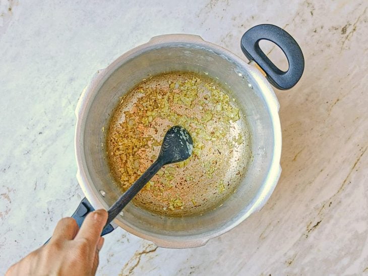 Cebola e alho dourados na panela de pressão.