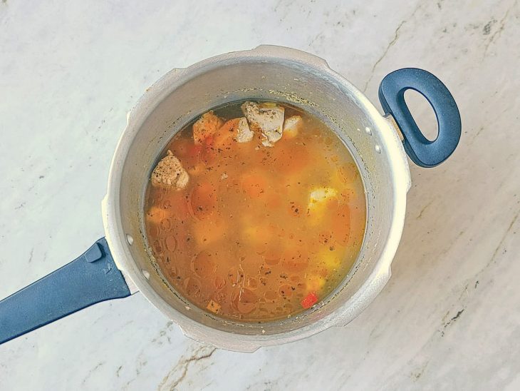 Frango coberto com água na panela.