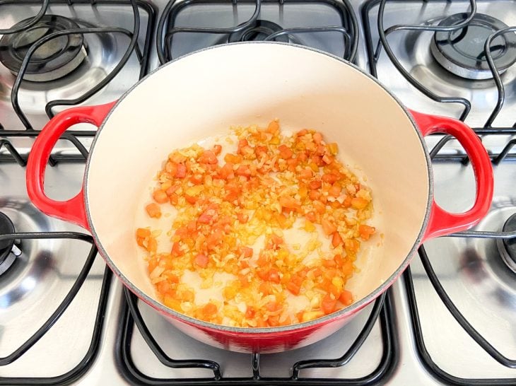 Uma panela com azeite, tomate e cebola picados.