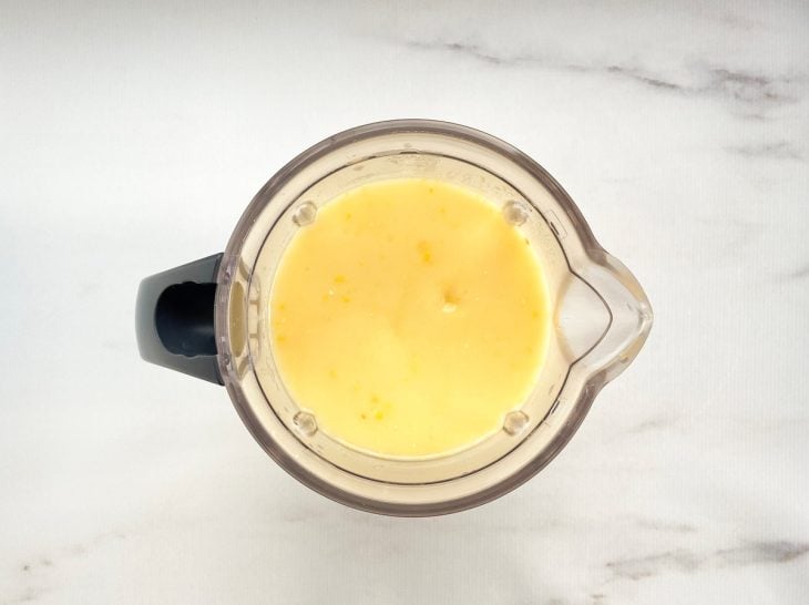Um liquidificador contendo água, mandioca e milho.