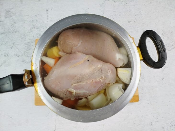 Peito de frango e legumes adicionados na panela de pressão para cozinhar.