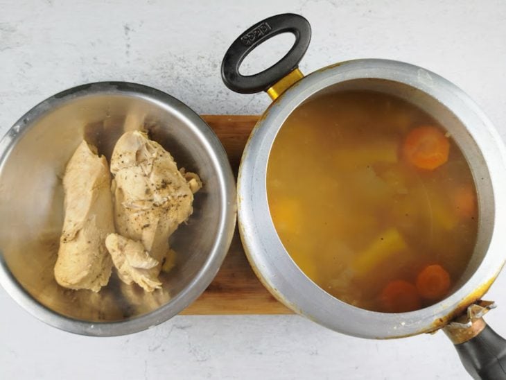 Peito de frango e mandioca retirados da panela e reservados em recipientes distintos.