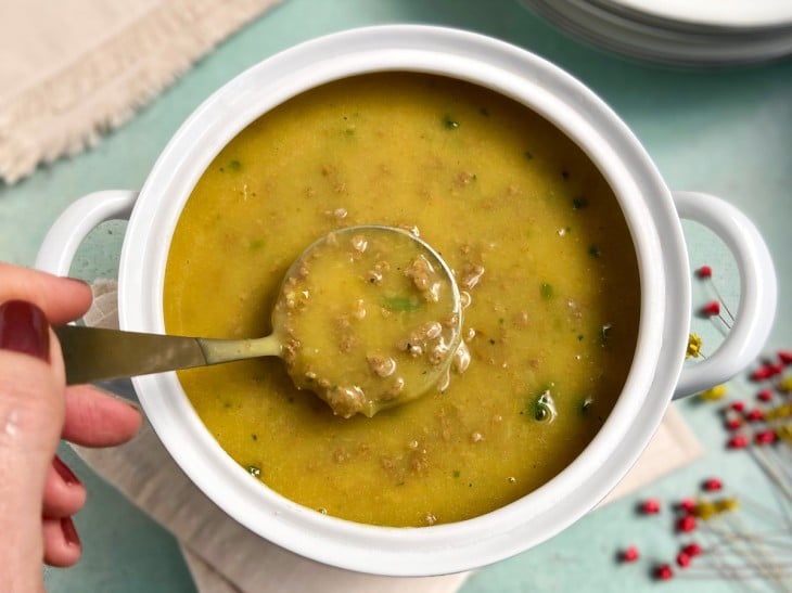 Caldo de mandioca com carne moída em um recipiente de cor branca.