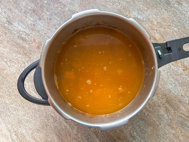 Panela com a cebola, carne, temperos e água.