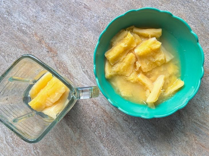 Tigela e liquidificador com pedaços de mandioca.