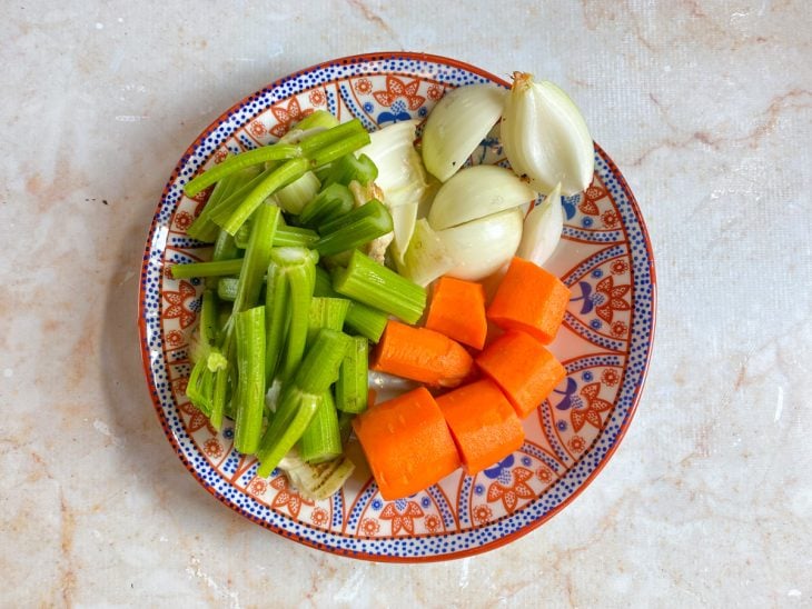 Um prato com alhos descascados e outros vegetais picados.