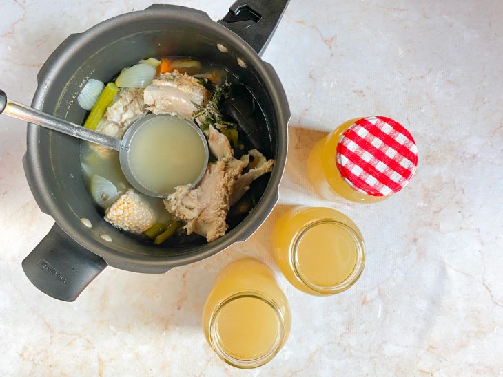 Caldo de peixe sendo retirado da panela com uma concha e colocado em potinhos.