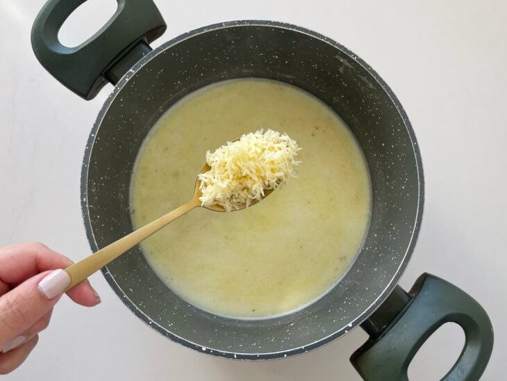 Parmesão sendo adicionado ao creme na panela.
