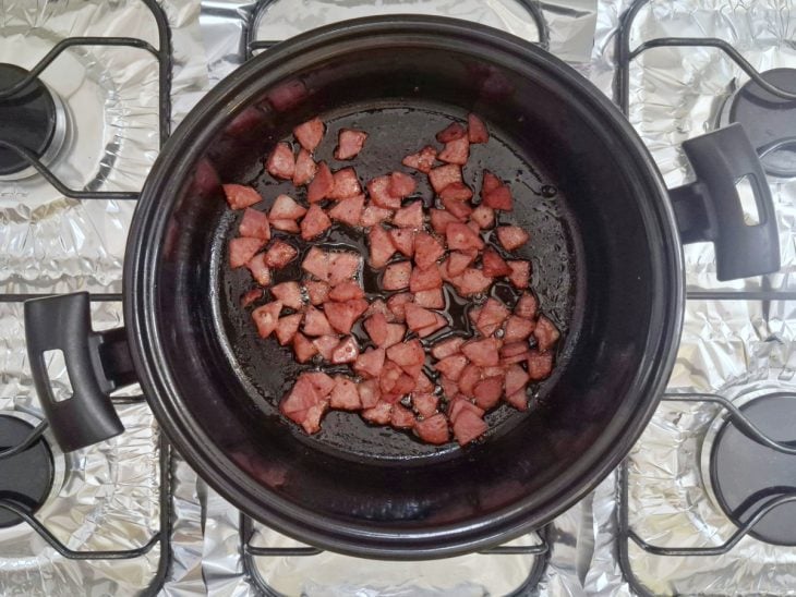 Cubos de calabresa fritos em uma panela.