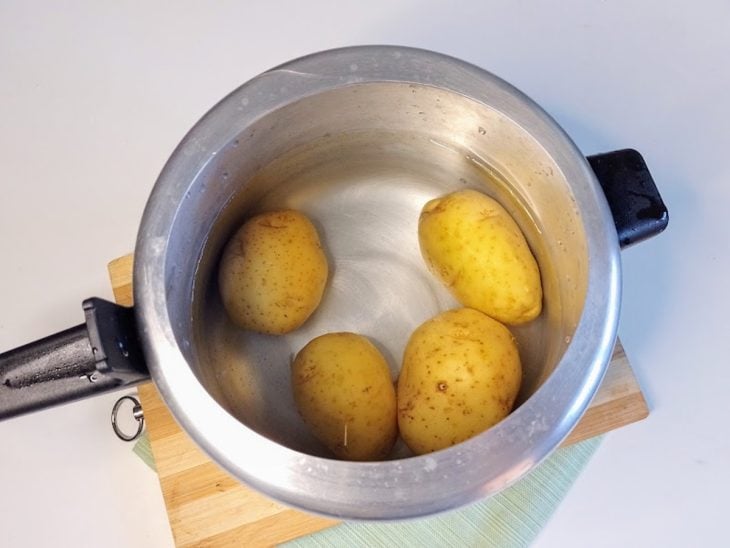 Uma panela de pressão contendo batatas cobertas por água.