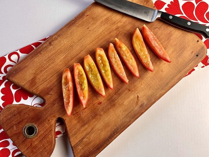 Uma tábua contendo tomates cortados em tiras sem sementes.
