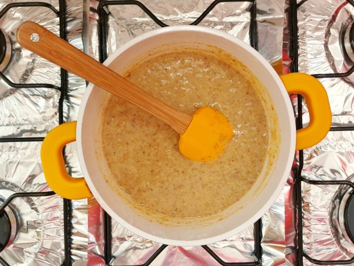 Uma panela contendo a mistura de leite condensado, gemas e nozes trituradas.