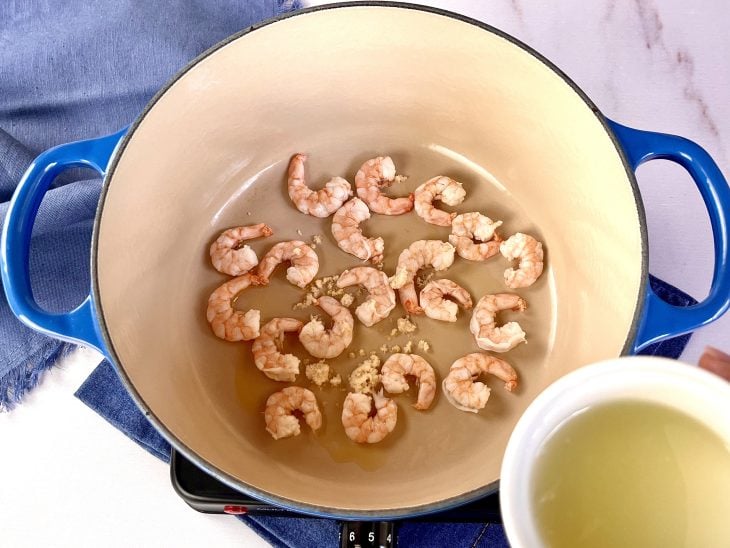 Caldo do limão-siciliano sendo adicionado à panela com camarão.