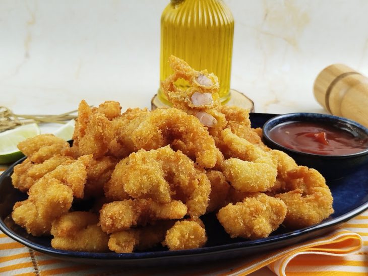 Camarão empanado pronto para consumo acompanhado por molho.