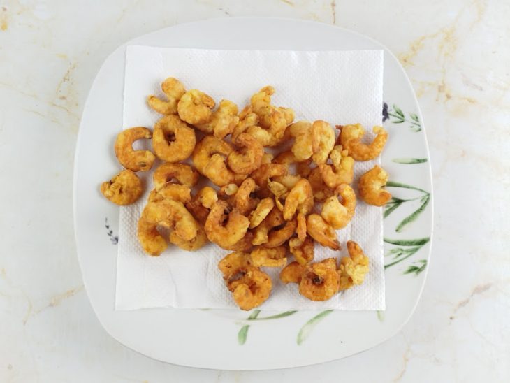 Camarões fritos escorrendo o óleo num papel toalha.