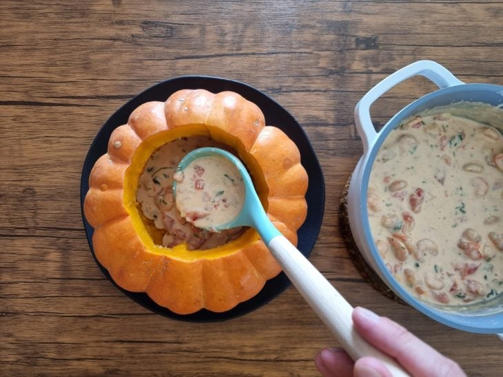 Creme de camarão sendo colocado dentro da abóbora moranga.