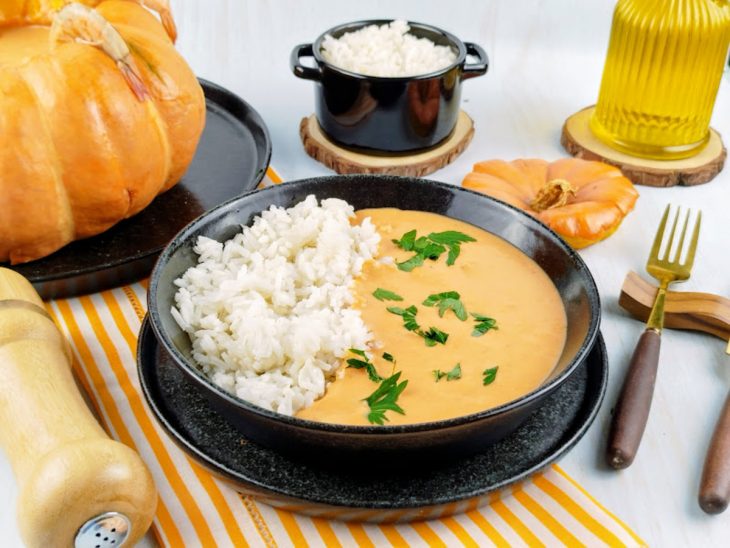 Camarão na moranga servido com arroz num prato individual.