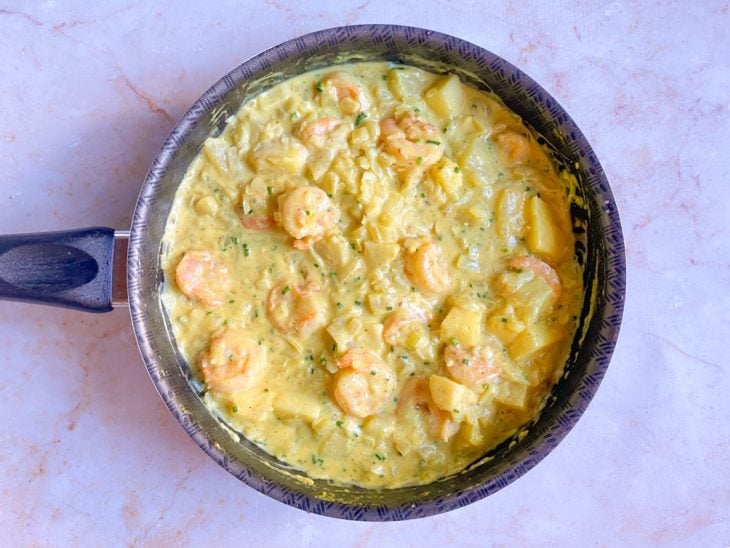 Camarões refogados, pimenta-do-reino, açafrão, cheiro-verde e cubos de abacaxi adicionados a panela.