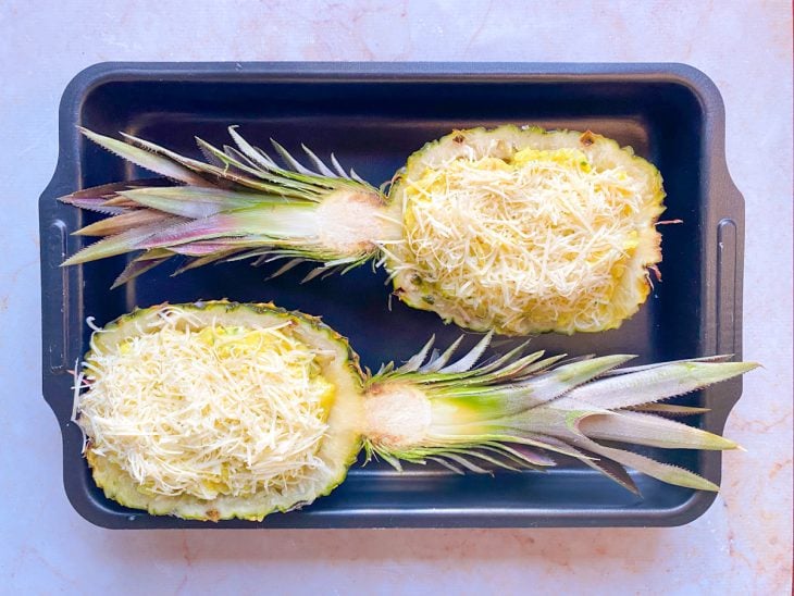 Creme de camarão dentro do abacaxi com queijo parmesão ralado em cima, ainda antes de assar.