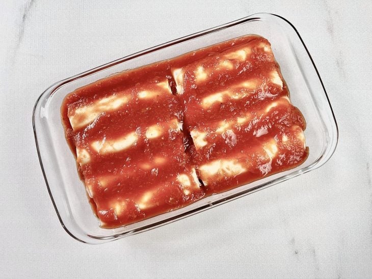 Canelones dispostos no refratário e cobertos por outra camada de passata rústica de tomate.