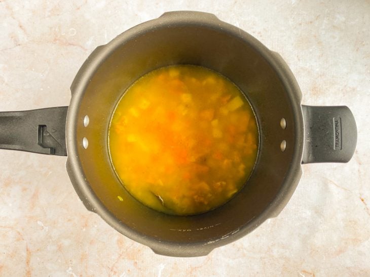 Legumes e arroz cru adicionado na panela.