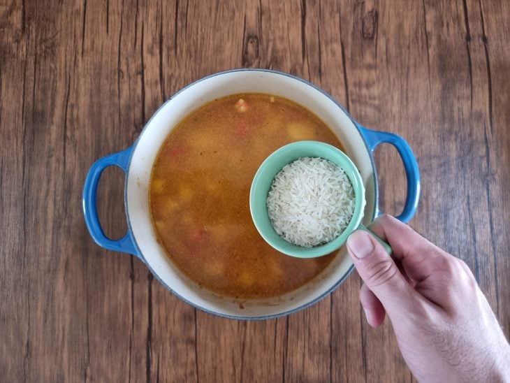 Arroz cru sendo adicionado na panela de canja de galinha simples.