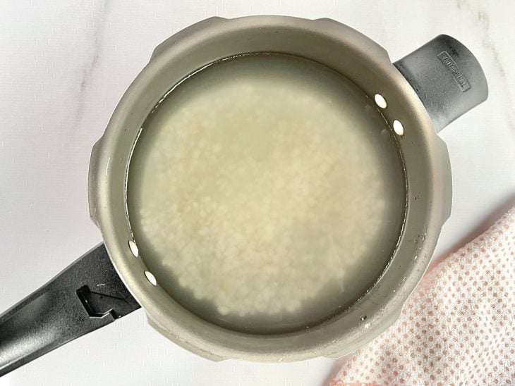Uma panela com canjica, água e açúcar.