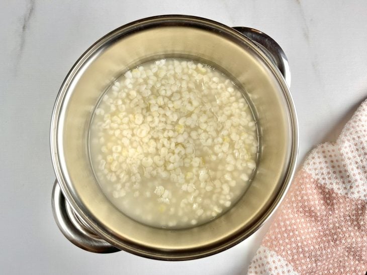 Uma panela com canjica, água e açúcar.