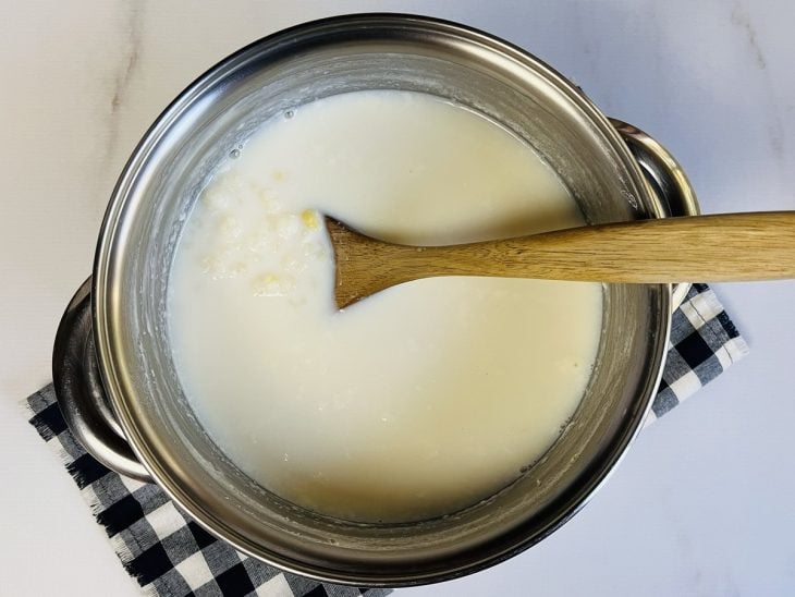 Uma panela contendo canjica, açúcar e leite.
