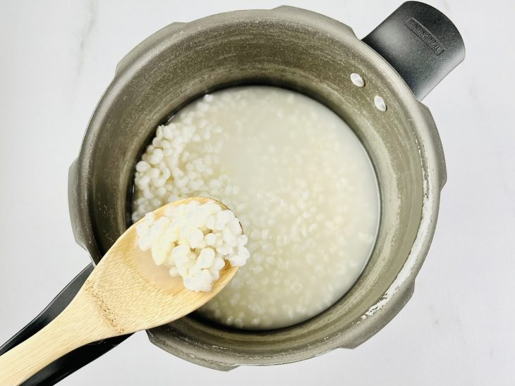 Na panela de pressão, uma porção da canjica tirada com colher para verificar ponto.