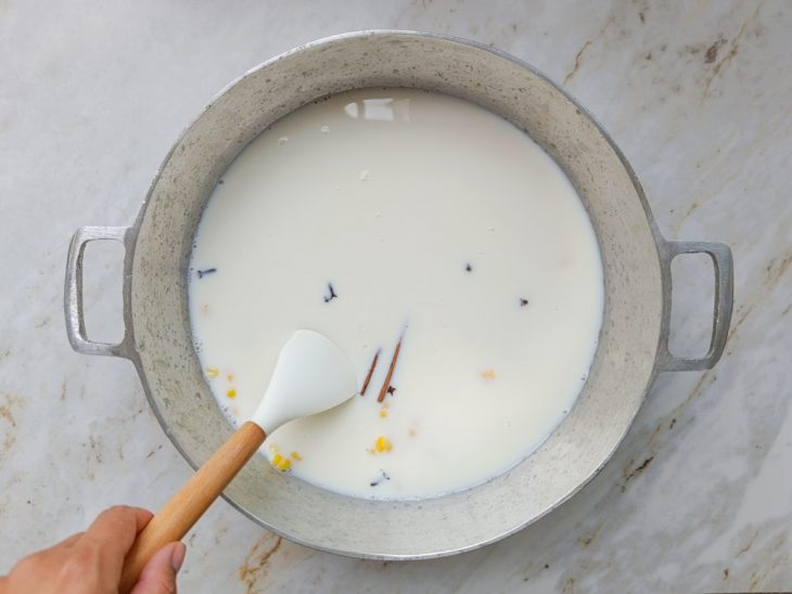 Canjica na panela com leite e especiarias adicionados.