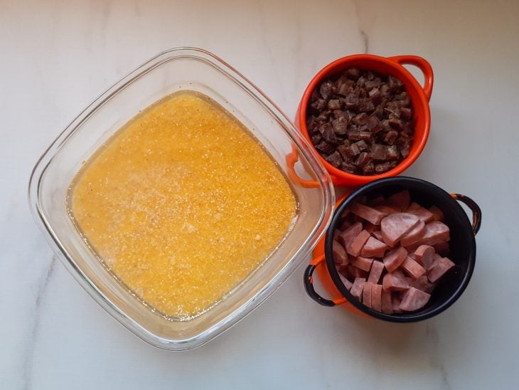 Recipiente contendo canjiquinha em demolho, calabresa picada e outras com carne picada.
