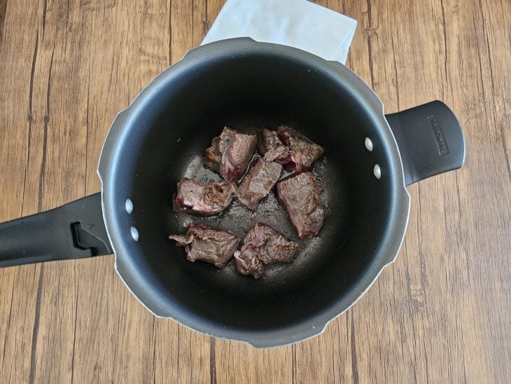 Uma panela de pressão com a carne selada.