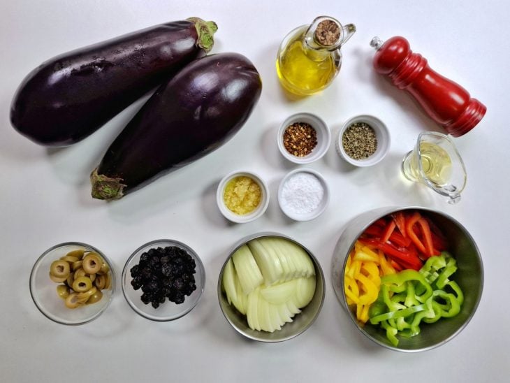 Ingredientes necessários para a receita de caponata de berinjela na panela reunidos em uma bancada.