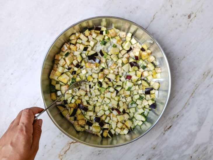 Ingredientes em cubo temperados numa assadeira.