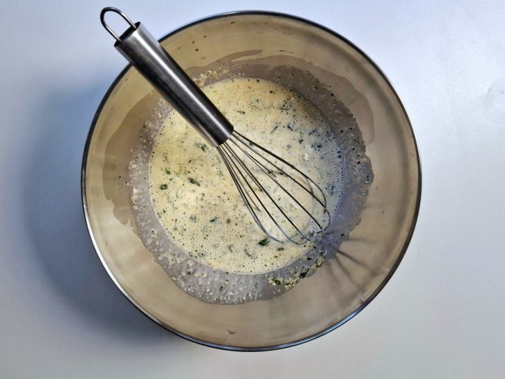 Tigela com ovos, queijo ralado, cheiro verde e creme de leite batidos.
