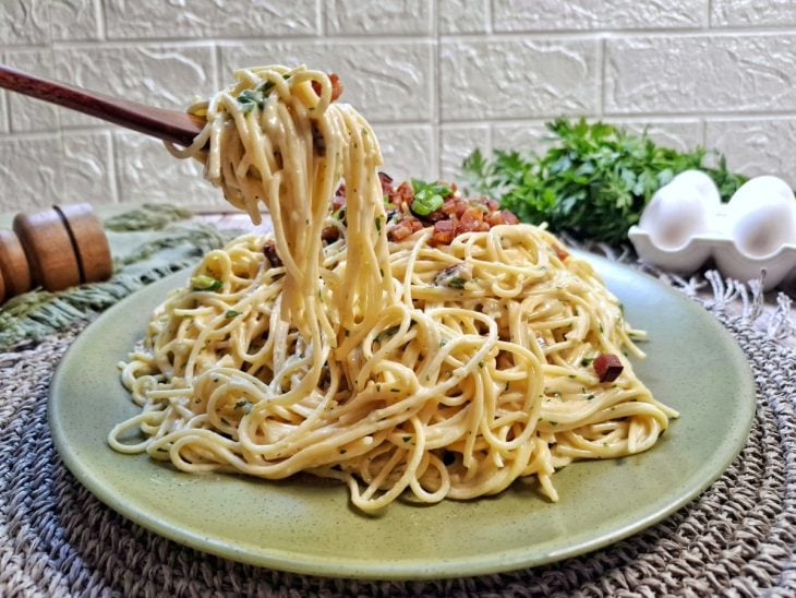 Carbonara com creme de leite em um prato finalizado com cubos de bacon.