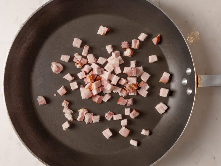 Bacon em cubos em uma frigideira.