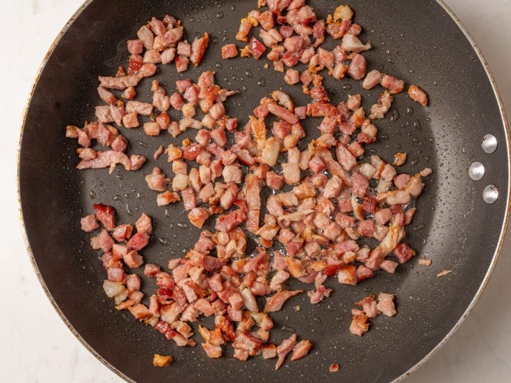 Bacon frito em uma frigideira.