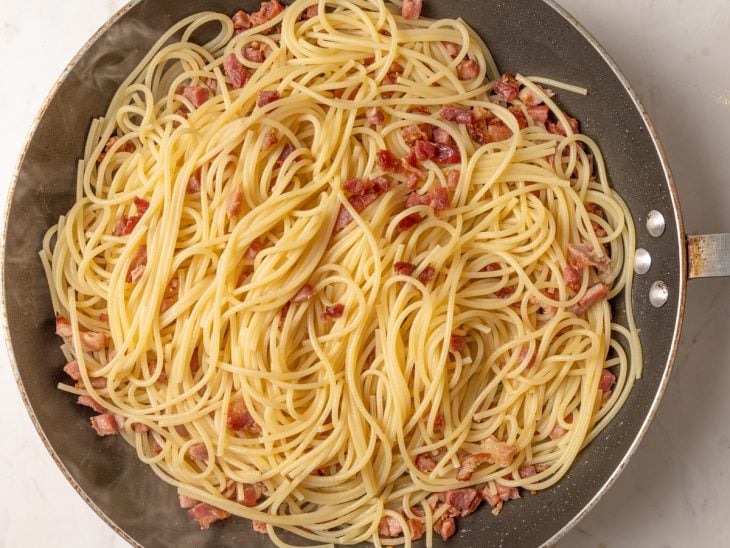 Frigideira com macarrão cozido e bacon frito.