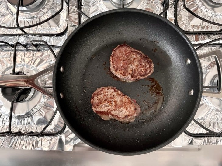 Uma frigideira com as carnes seladas.