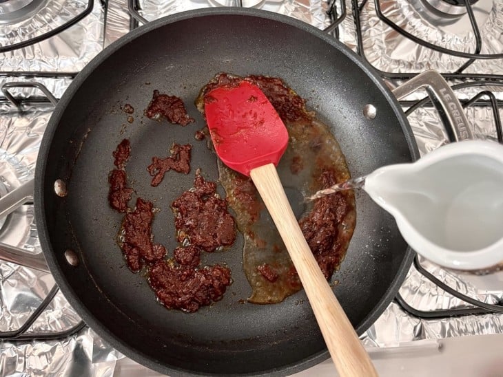 Uma frigideira com o molho e água quente.