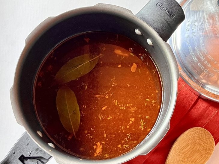 Uma panela de pressão contendo carne coberta com caldo.