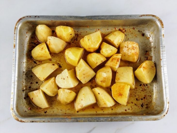 batatas temperadas em tabuleiro prontas para irem ao forno.